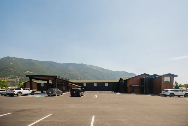 Riverstone hotel full exterior under blue Montana sky with forested mountain range backdrop