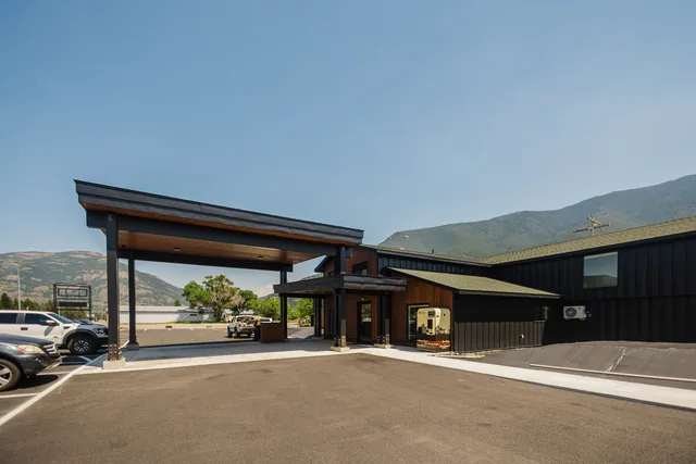 Covered porte-cochere entry canopy with warm cedar ceiling and Montana mountains framed through the opening