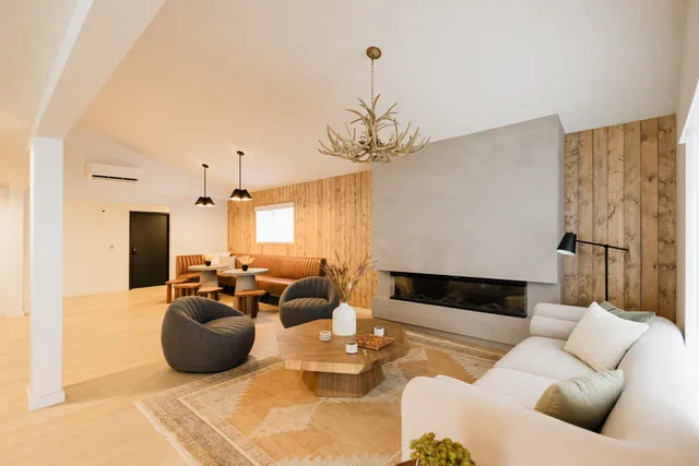 Riverstone lobby from entry showing full depth: leather banquette, pendant lights, fireplace lounge, and antler chandelier beyond