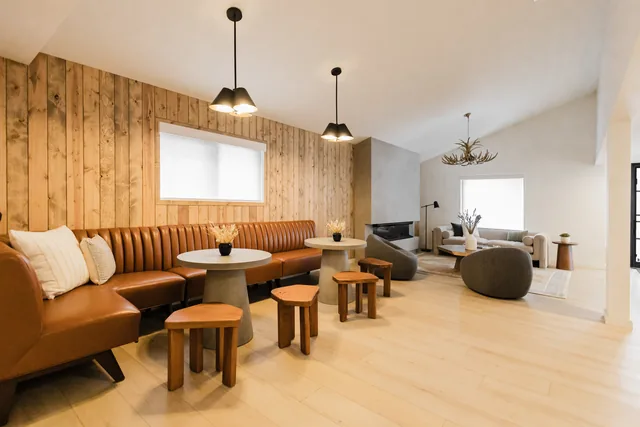 Lobby social seating area connecting cognac leather banquette and stone fireplace lounge under warm pendant lights