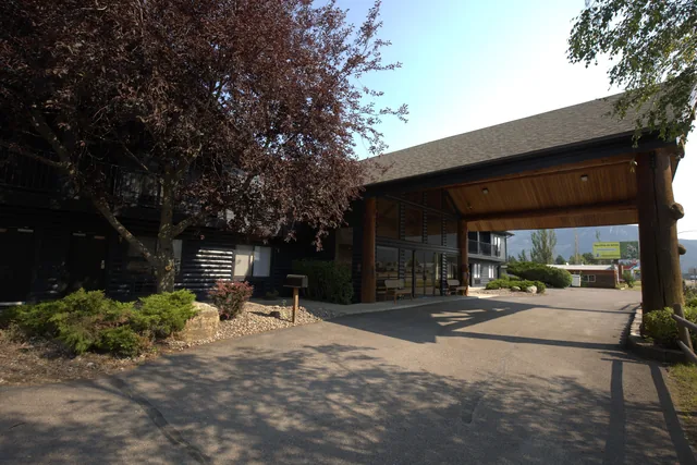 Timber porte-cochère entrance framing the hotel drive with mountains visible in the background