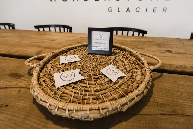 Woven seagrass tray holding Wonderstone branded key card envelopes on the communal table, check-out sign in the background
